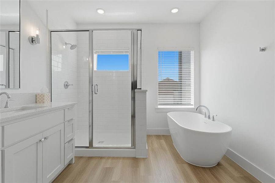 Freestanding soaking tub complemented by a separate glass-enclosed shower with subway tile surround