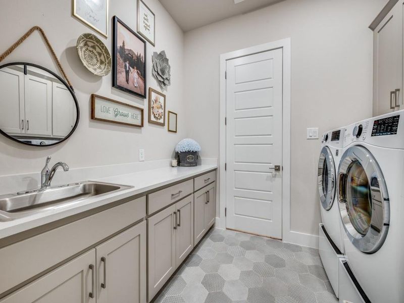 Laundry area featuring washer and dryer, cabinet space, and light tile patterned flooring