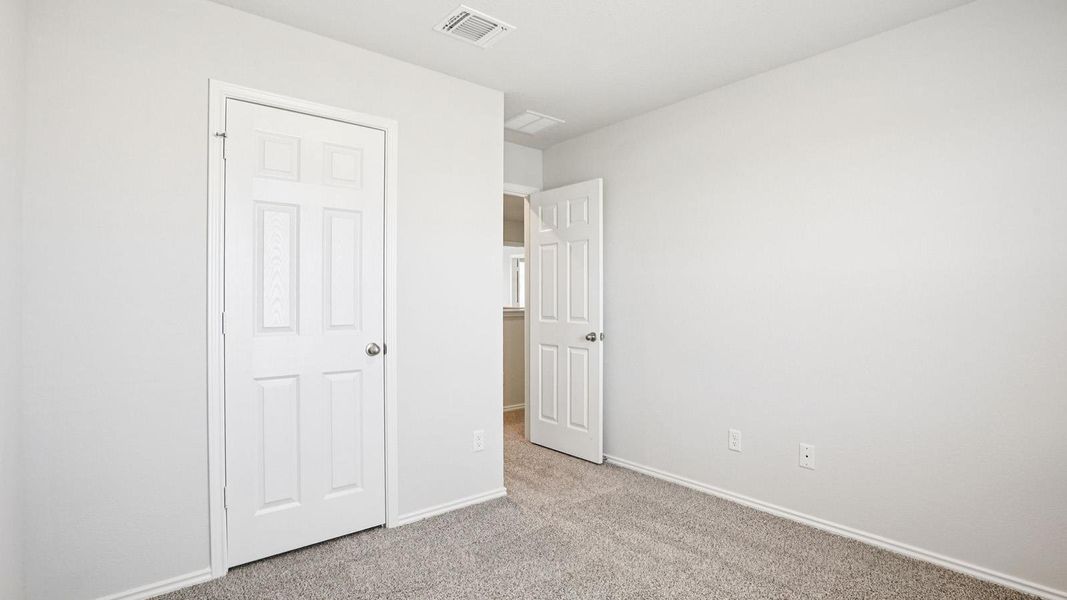 Bedroom featuring light gray wall paint, gray carpet flooring, white trim, and a white paneled door