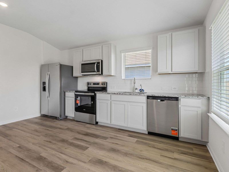 Gleaming stone countertops and modern flooring anchor this airy, light-filled kitchen space.