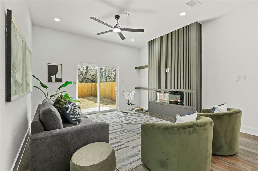 Living room featuring a glass covered fireplace, ceiling fan, recessed lighting, and wood finished floors Living room featuring a glass covered fireplace, ceiling fan, recessed lighting, and wood finished floors