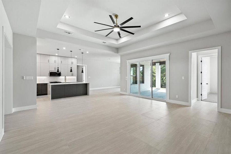 Unfurnished living room featuring a raised ceiling, ceiling fan, and recessed lighting Unfurnished living room featuring a raised ceiling, ceiling fan, and recessed lighting