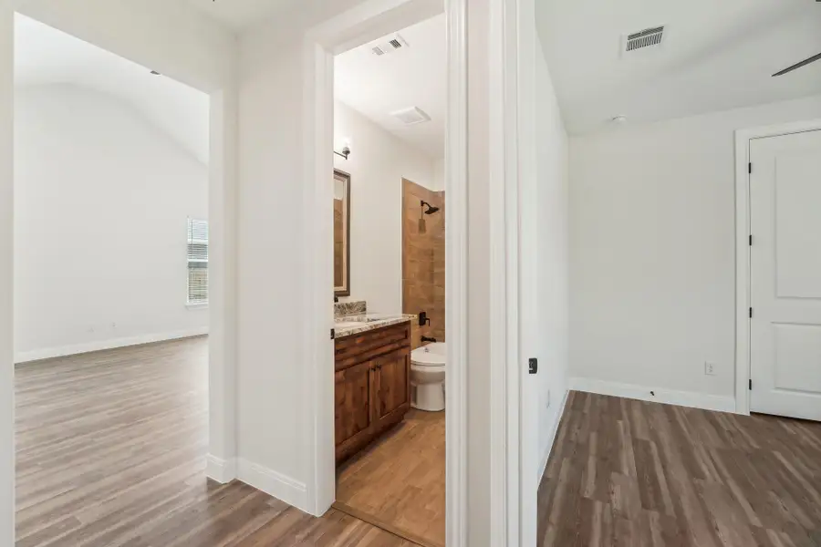 Corridor with vaulted ceiling, baseboards, wood-style vinyl flooring and visible vents Corridor with vaulted ceiling, baseboards, wood-style vinyl flooring and visible vents