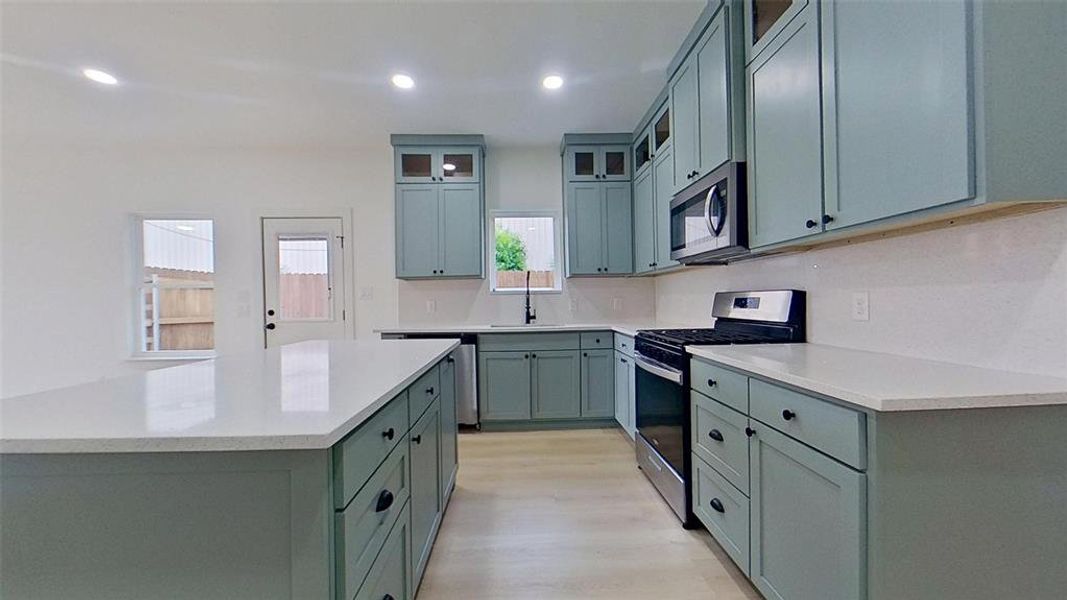 Contemporary kitchen featuring light blue cabinetry and light-toned countertops