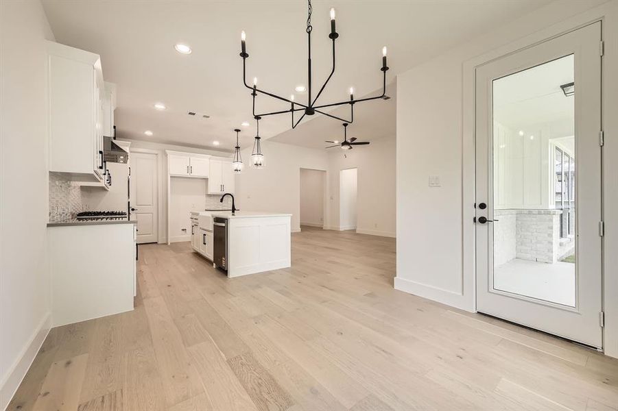 Kitchen featuring a chandelier, tasteful backsplash, recessed lighting, open floor plan, and white cabinetry