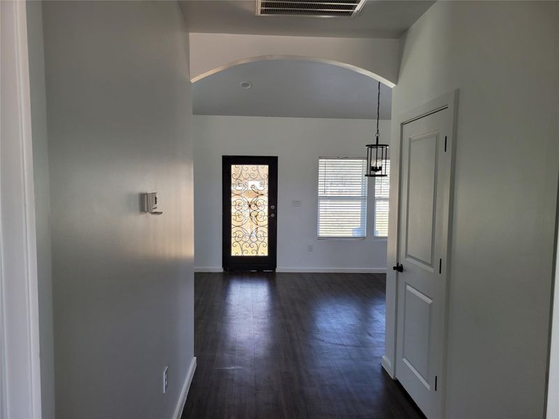 An inviting entry opens to a spacious living area, highlighted by elegant dark wood flooring and natural light.