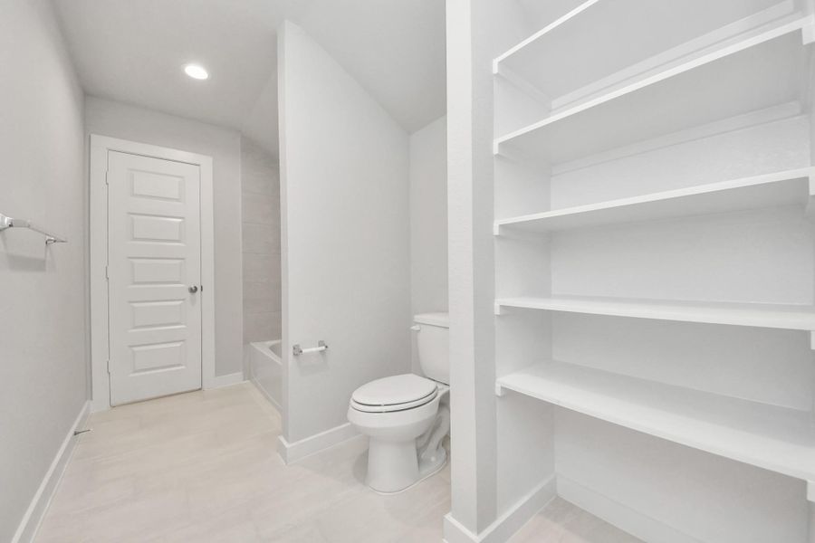 Experience convenience in the secondary bathroom, designed for Jack and Jill arrangements, now with a separate vanity area. This well-appointed space showcases stylish tile flooring, a bath/shower combo with an elegant tile surround, and light-stained wood cabinets. The beautiful light countertop adds a touch of sophistication, combining functionality and aesthetics seamlessly. Sample photo of completed home with similar floor plan. Actual colors and selections may vary. Experience convenience in the secondary bathroom, designed for Jack and Jill arrangements, now with a separate vanity area. This well-appointed space showcases stylish tile flooring, a bath/shower combo with an elegant tile surround, and light-stained wood cabinets. The beautiful light countertop adds a touch of sophistication, combining functionality and aesthetics seamlessly. Sample photo of completed home with similar floor plan. Actual colors and selections may vary.