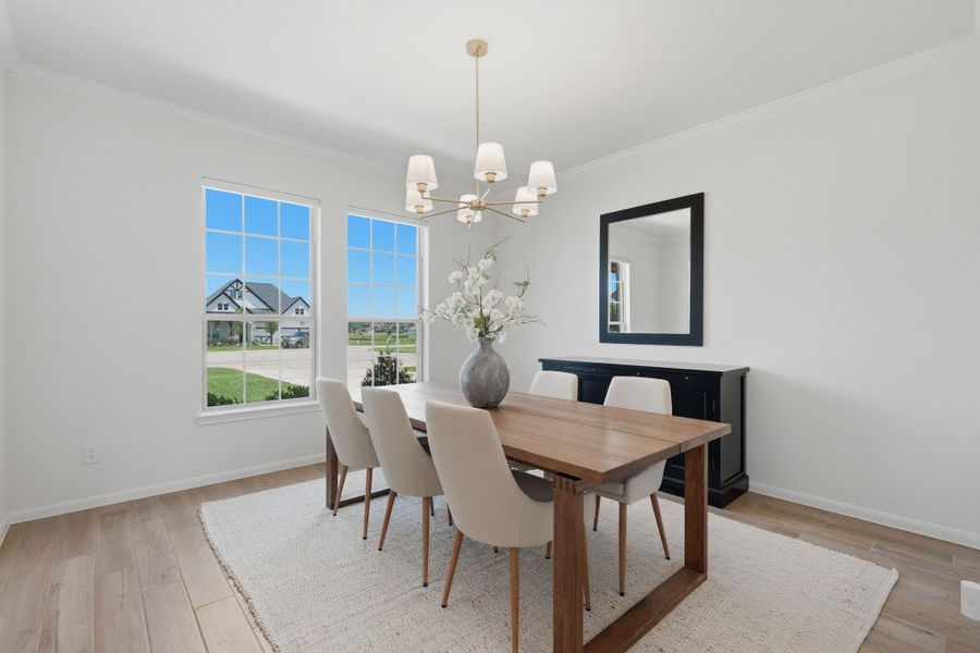 Bright and inviting dining room featuring large windows, a modern chandelier, and a wooden table. Neutral walls and hardwood floors create a warm, elegant atmosphere.