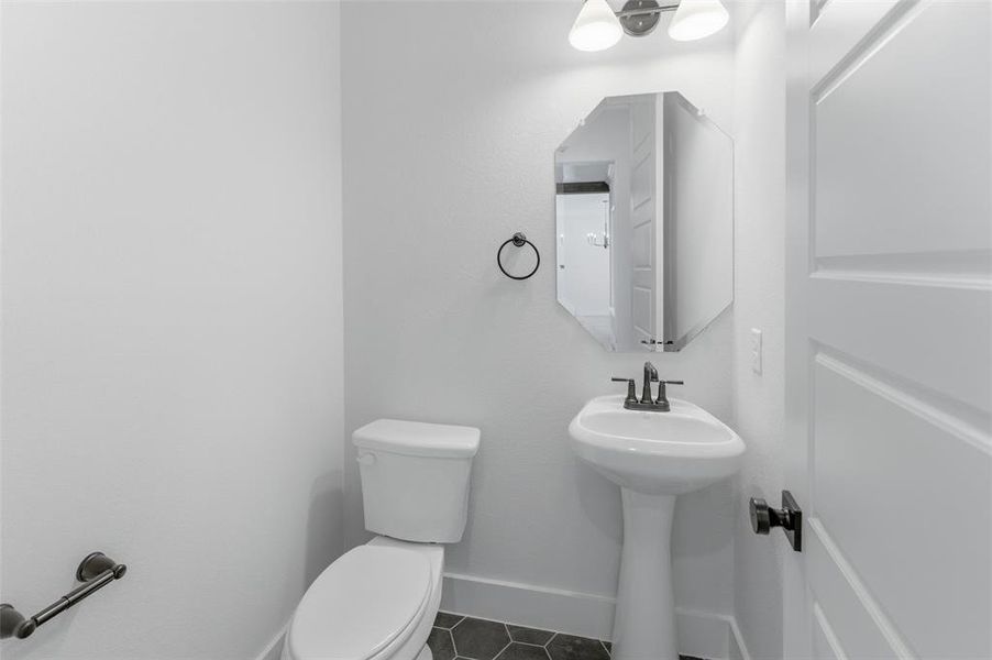 Half bath featuring toilet and dark tile patterned flooring
