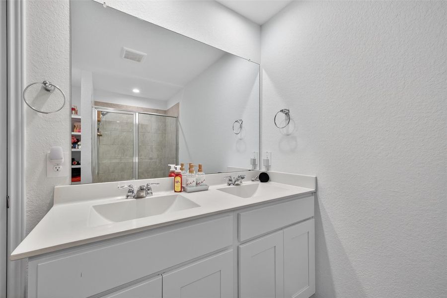 Dual vanities, exquisite finishes, and a walk-in shower create a luxurious atmosphere.