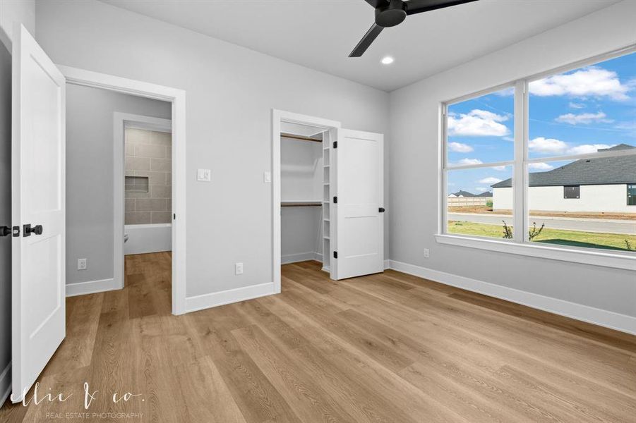 Unfurnished bedroom featuring a spacious closet, ceiling fan, light wood-style flooring, and recessed lighting
