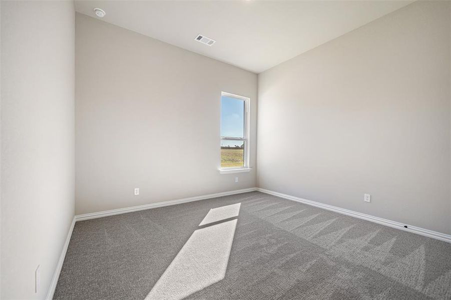 Carpeted spare room featuring baseboards
