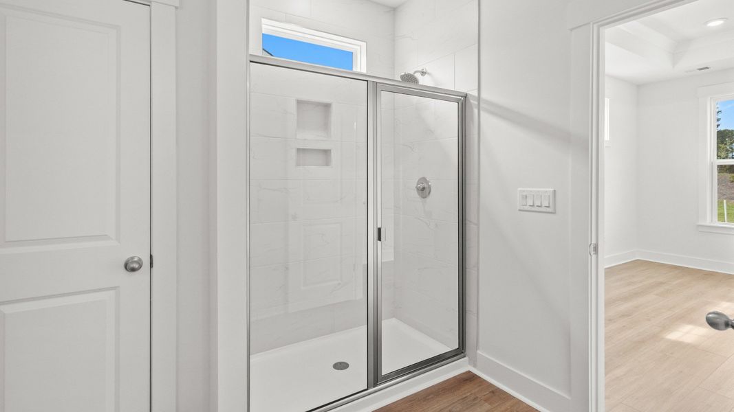 Elegant glass-tiled shower in the primary bathroom adds spa-like comfort. Elegant glass-tiled shower in the primary bathroom adds spa-like comfort.