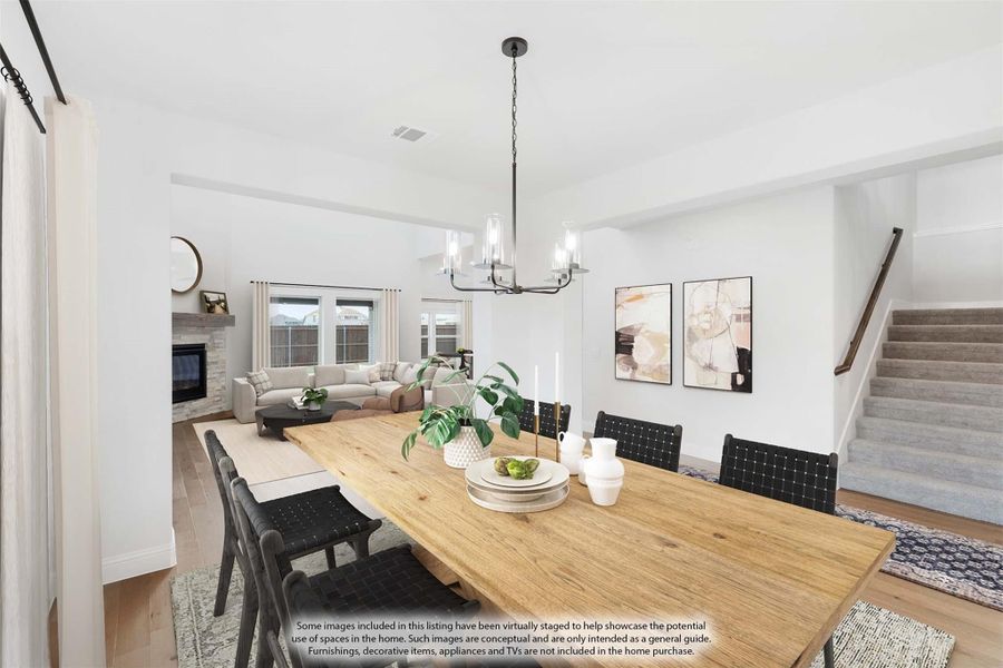 Dining area with wood table and black chairs, open to living room with fireplace and staircase nearby Dining area with wood table and black chairs, open to living room with fireplace and staircase nearby