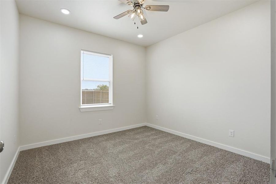 Neutral-toned interior featuring recessed lighting, a ceiling fan with integrated light fixture, a single window, and textured carpet flooring