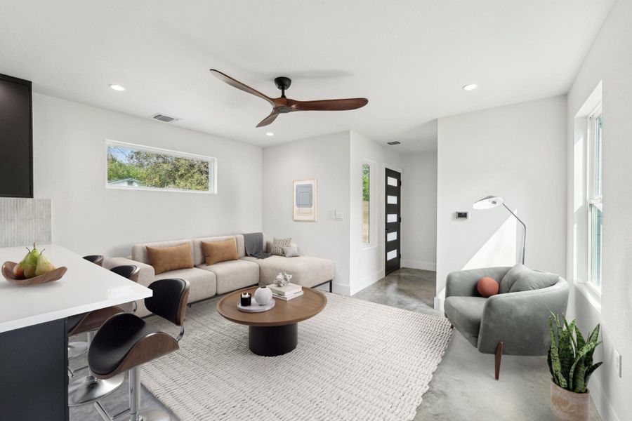 Living room with a ceiling fan, recessed lighting, finished concrete floors, and baseboards