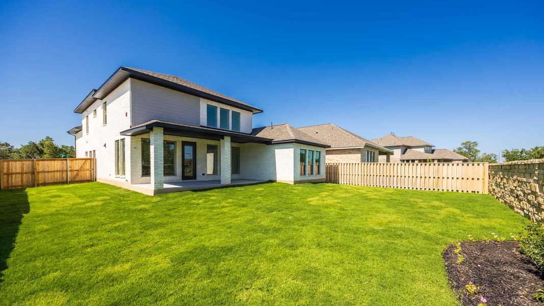 Rear view of property with brick siding, a fenced backyard, and a patio area