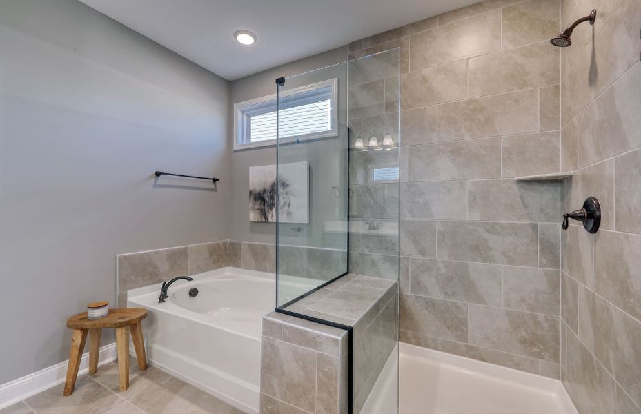 The Owner's Walk-in features a spacious layout with a soaking tub and a custom-built bench in the frameless shower.