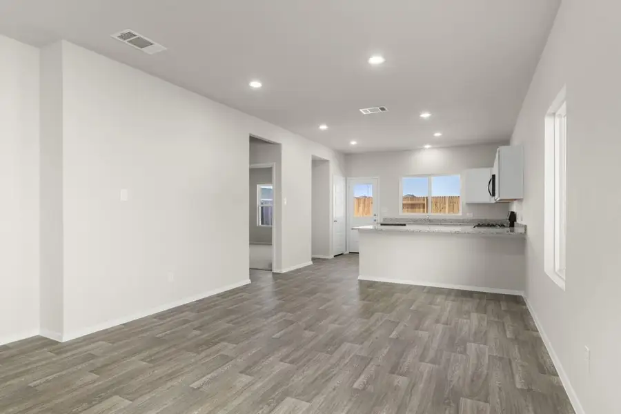Image of a dining room area with beige walls, windows, a connecting kitchen and a back white door Image of a dining room area with beige walls, windows, a connecting kitchen and a back white door