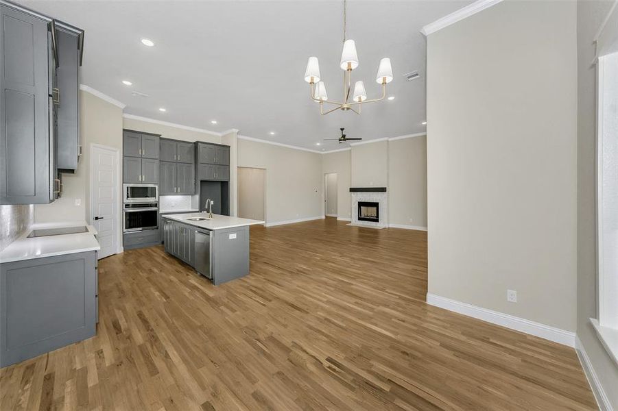 Kitchen with sink, pendant lighting, a kitchen island with sink, appliances with stainless steel finishes, and hardwood / wood-style flooring