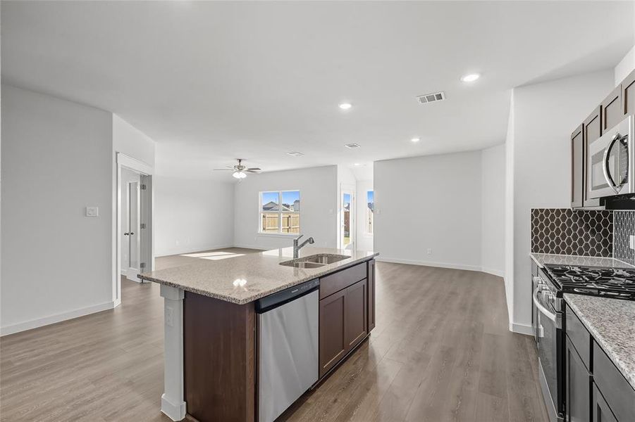 Kitchen with stainless steel appliances, open floor plan, backsplash, recessed lighting, and light wood finished floors Kitchen with stainless steel appliances, open floor plan, backsplash, recessed lighting, and light wood finished floors