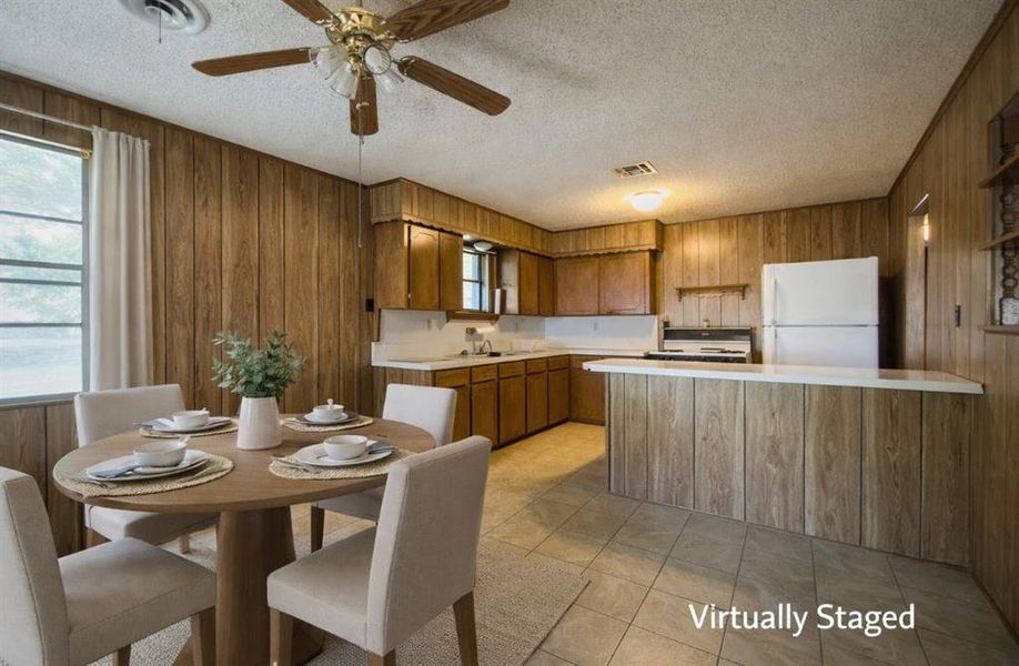 Kitchen with wood finish cabinetry, light countertops, a peninsula, freestanding refrigerator, and a textured ceiling