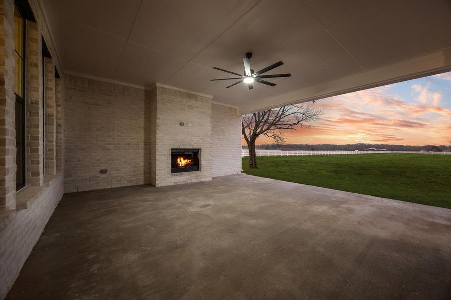 Patio terrace at dusk featuring ceiling fan, a patio, and an outdoor brick fireplace