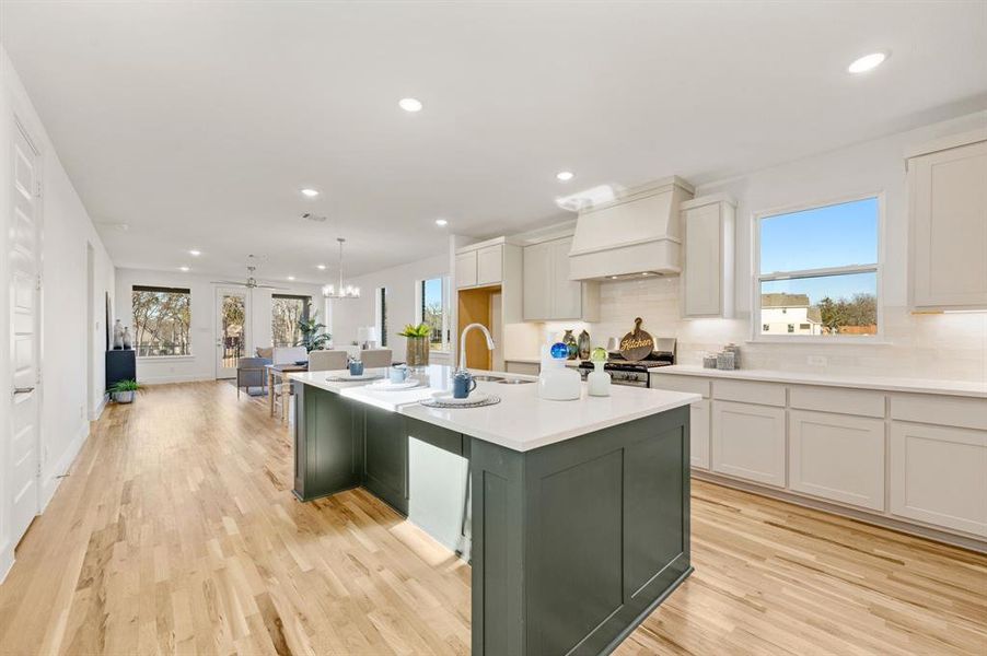 Two tone kitchen with an island with sink, two tone cabinetry, tasteful backsplash, gas range, and open floor plan