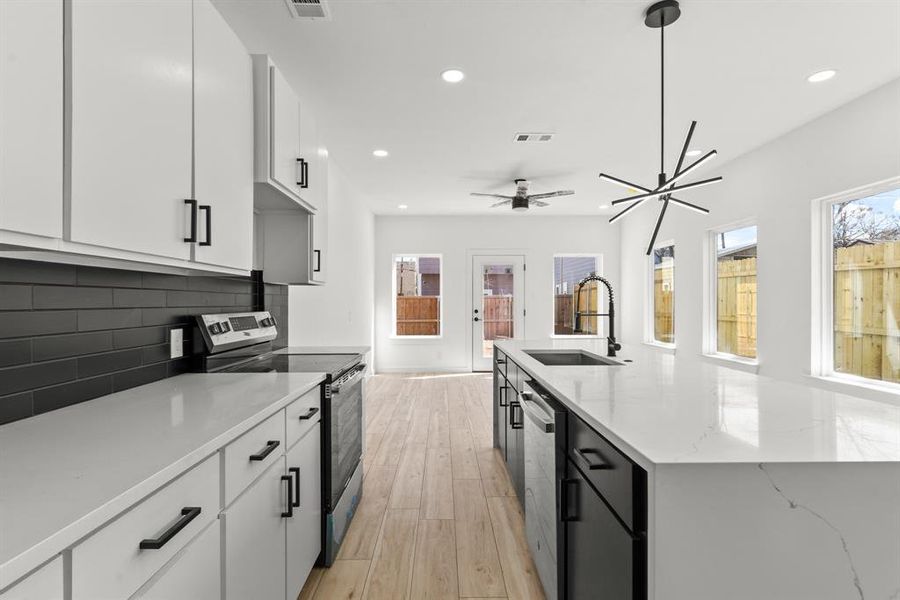 Kitchen featuring stainless steel appliances, a sink, visible vents, backsplash, and light wood finished floors