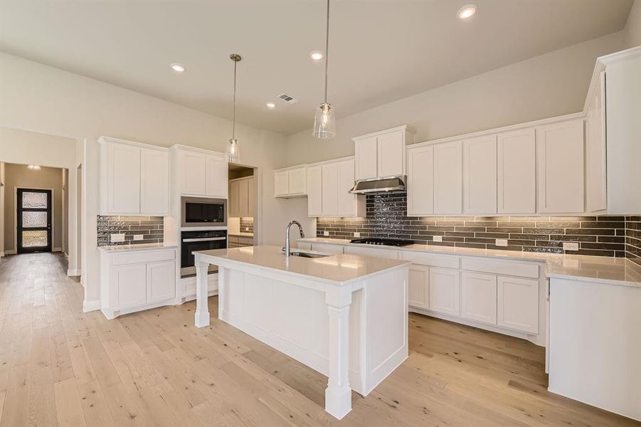 Kitchen featuring white cabinets, black gas cooktop, ventilation hood, stainless steel oven, and built in microwave