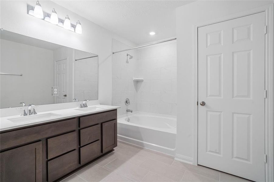 This primary bathroom is definitely move-in ready! Featuring an oversized tub/shower combo with tile surround, stained cabinets with light countertops, spacious walk-in closet with shelving, high ceilings, neutral paint, sleek and modern finishes.