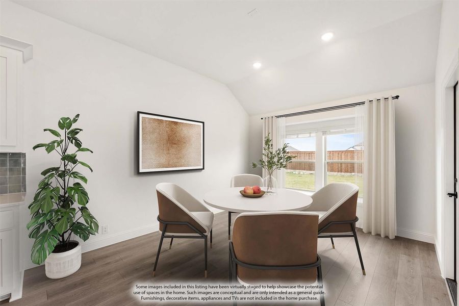Dining area with round white table, four chairs, vaulted ceiling, and large window with backyard view