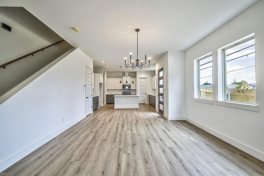 Unfurnished living room featuring an inviting chandelier and light wood-type flooring