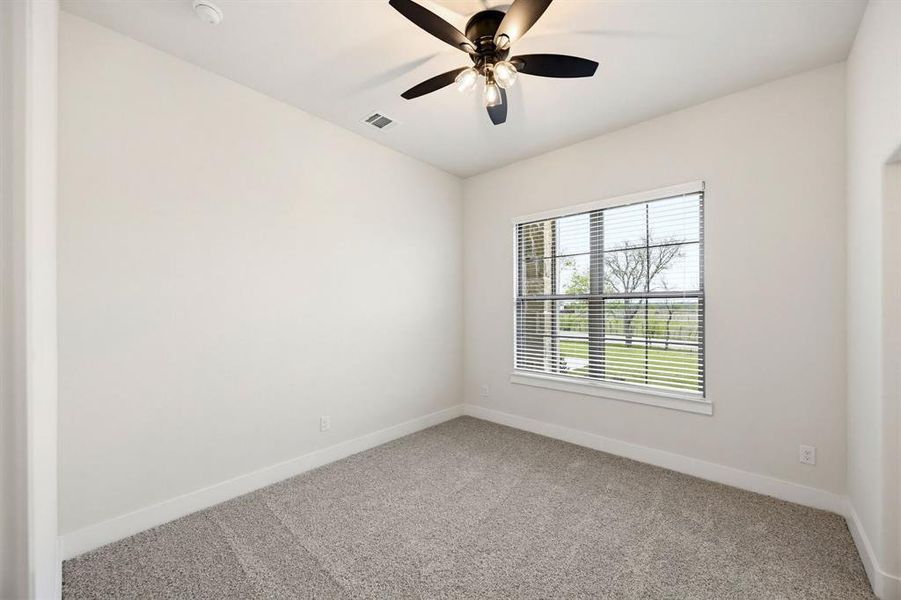 Bright room with a large window, plush carpet, contemporary ceiling fan, and white baseboards