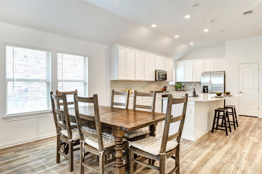 Dining space with plenty of natural light, light wood-style flooring, recessed lighting, and lofted ceiling
