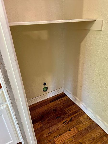 Laundry area with dryer hookup and a textured wall and dark wood finished floors