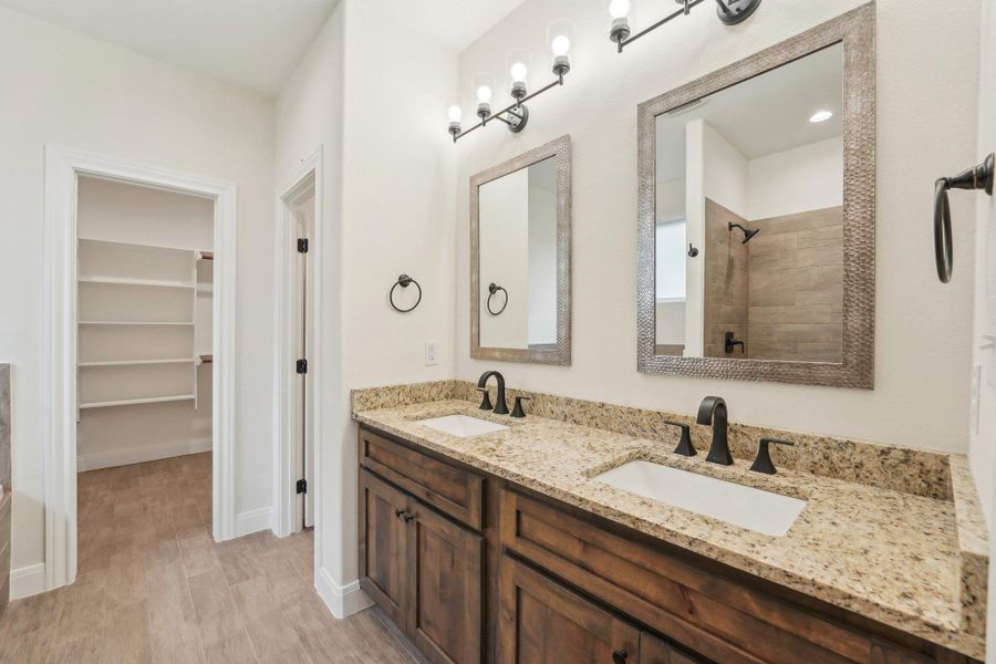 Full bath featuring a walk in closet, double vanity, tiled shower, and a sink Full bath featuring a walk in closet, double vanity, tiled shower, and a sink