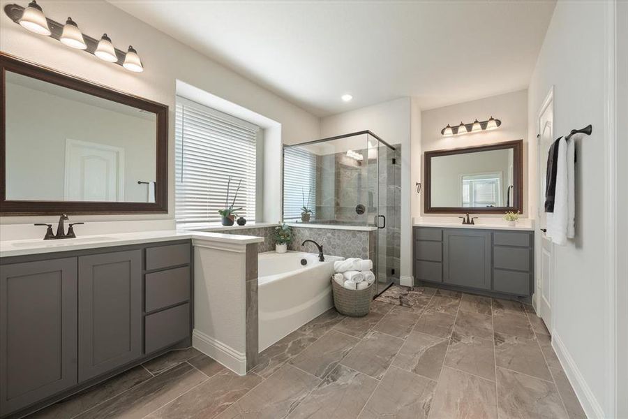 The primary bathroom has beautiful tiled flooring, separate vanities with quartz counters, framed mirrors, a garden tub and separate shower.