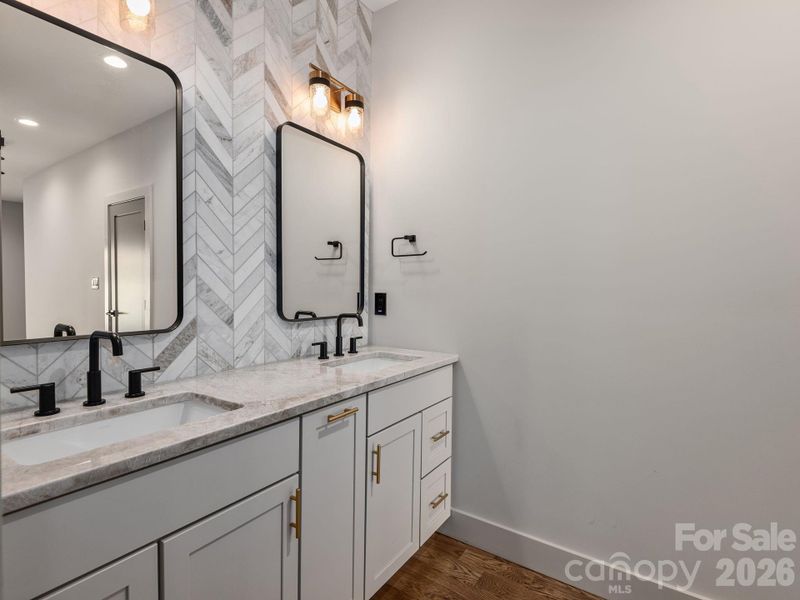 Representative photo from 50 Verde Drive showing the builder’s quality of construction and finish level, including a primary ensuite with Wolf cabinetry, granite countertops, dual sinks, designer mirrors, and a striking tiled accent wall.