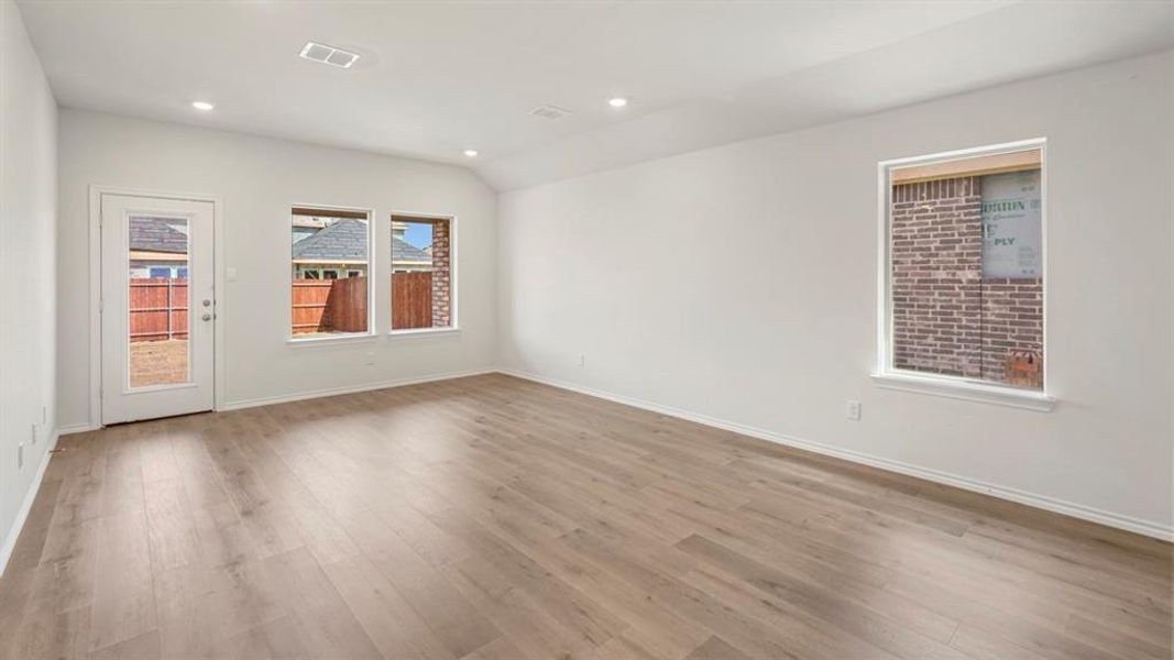 Spacious room featuring wood-finish flooring, recessed lighting, and white walls