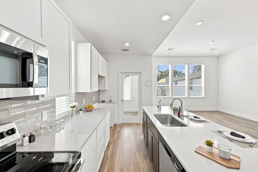 Another view highlighting the kitchen's generous counter space, cabinetry, stainless steel appliances, and open connection to the living area. Another view highlighting the kitchen's generous counter space, cabinetry, stainless steel appliances, and open connection to the living area.