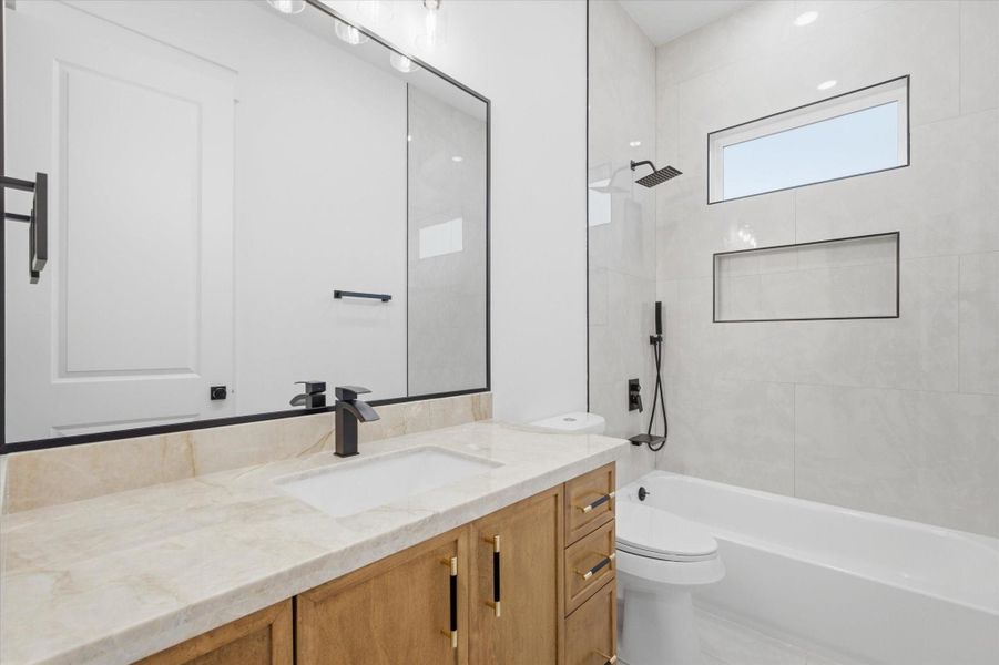 Contemporary Comfort. This beautiful full bathroom features a warm wood vanity with a luxurious marble-patterned countertop, sleek matte black hardware, and a modern tub-to-ceiling tiled shower complete with a built-in shampoo niche and a privacy window.