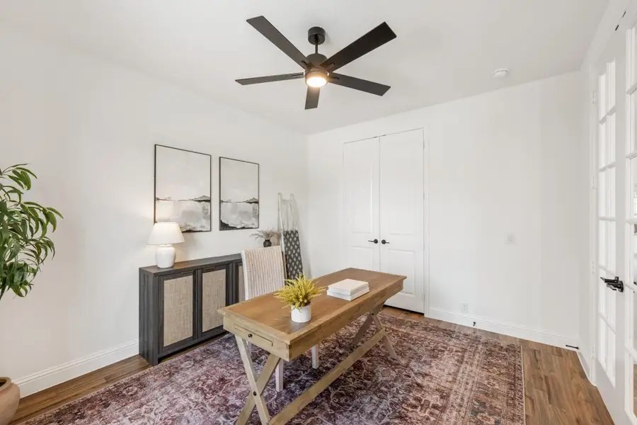 Home office with wood desk, ceiling fan, hardwood floors, and patterned area rug