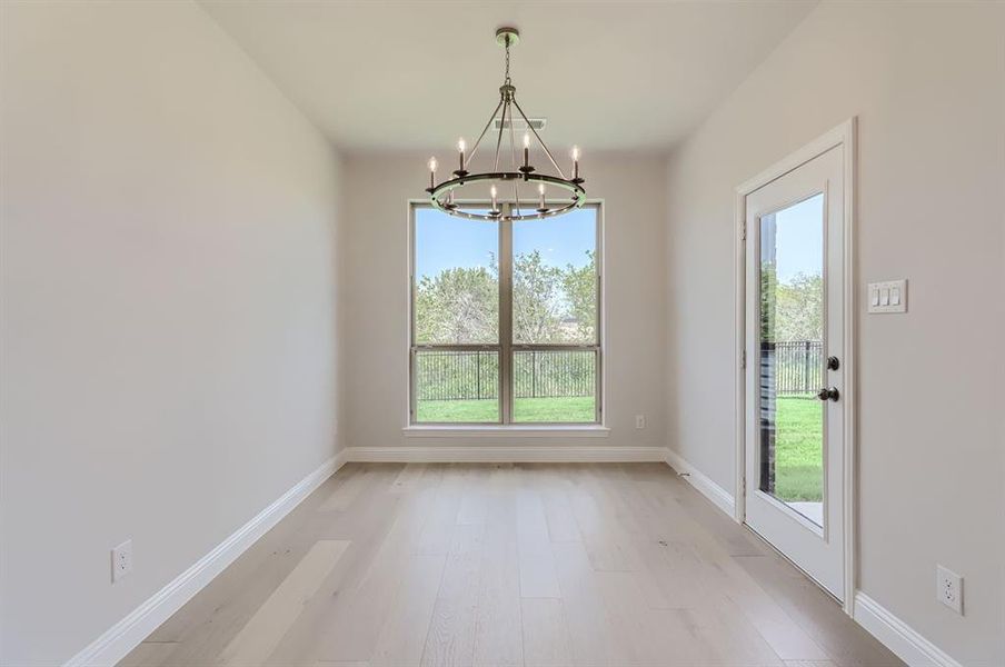 Unfurnished dining area with a notable chandelier, light hardwood / wood-style flooring, and a healthy amount of sunlight