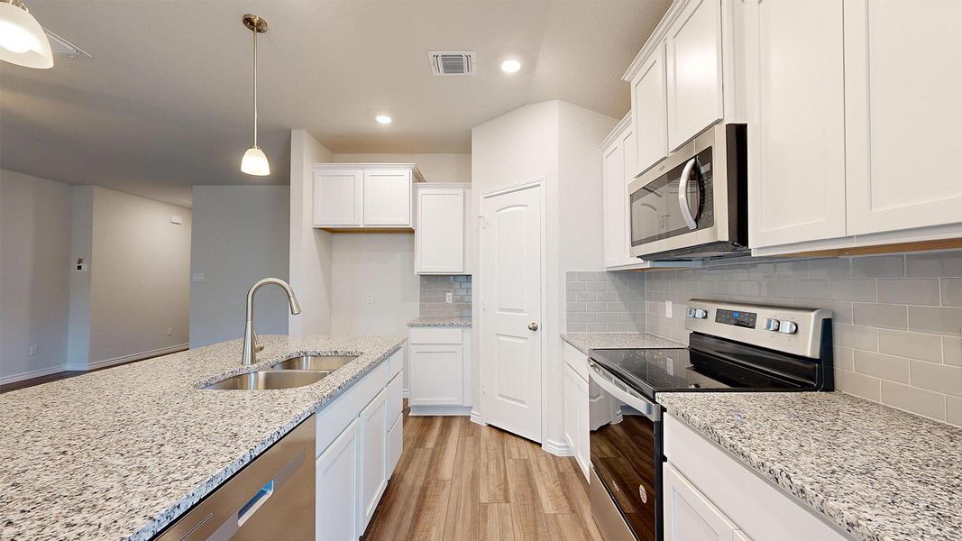 Kitchen with stainless steel appliances, light wood-style floors, white cabinets, tasteful backsplash, and pendant lighting Kitchen with stainless steel appliances, light wood-style floors, white cabinets, tasteful backsplash, and pendant lighting