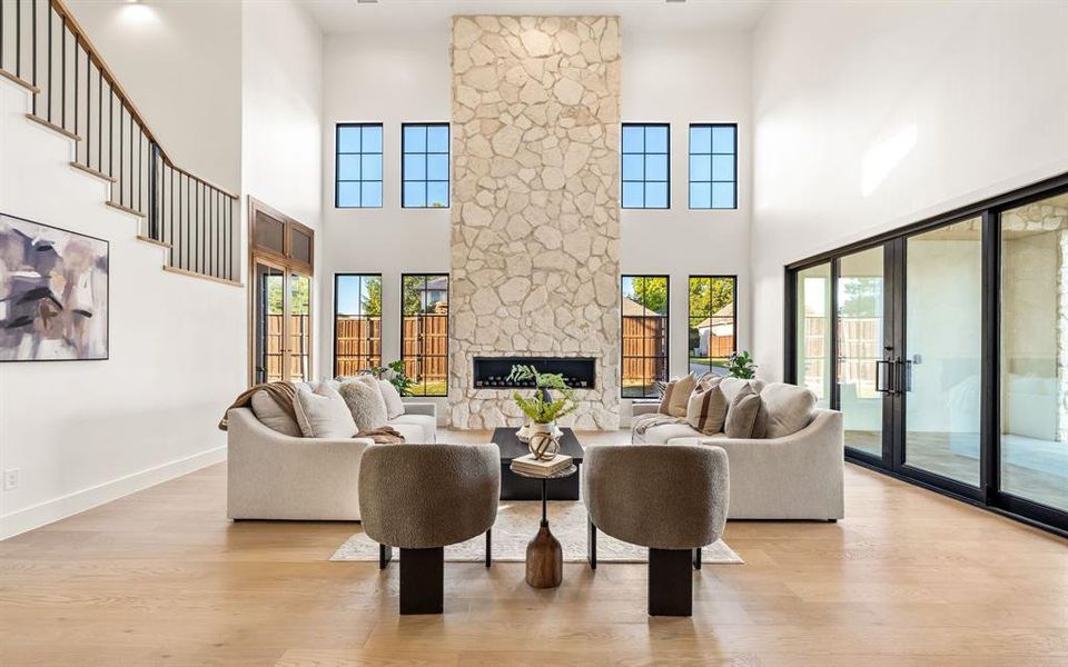 Living room featuring light wood-style floors, a stone fireplace, and healthy amount of natural light Living room featuring light wood-style floors, a stone fireplace, and healthy amount of natural light