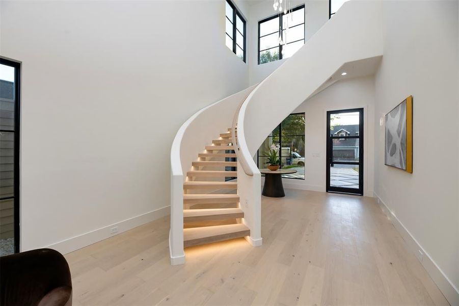 Foyer featuring light wood-style floors, stairway, and a towering ceiling