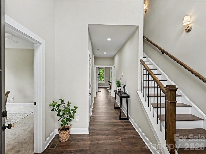 Step into this bright and inviting entryway featuring soaring ceilings, rich hardwood floors, and a stunning staircase that sets the tone for the home’s modern design.