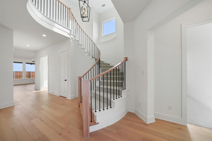 Stairway featuring plenty of natural light, wood finished floors, recessed lighting, a high ceiling, and a chandelier