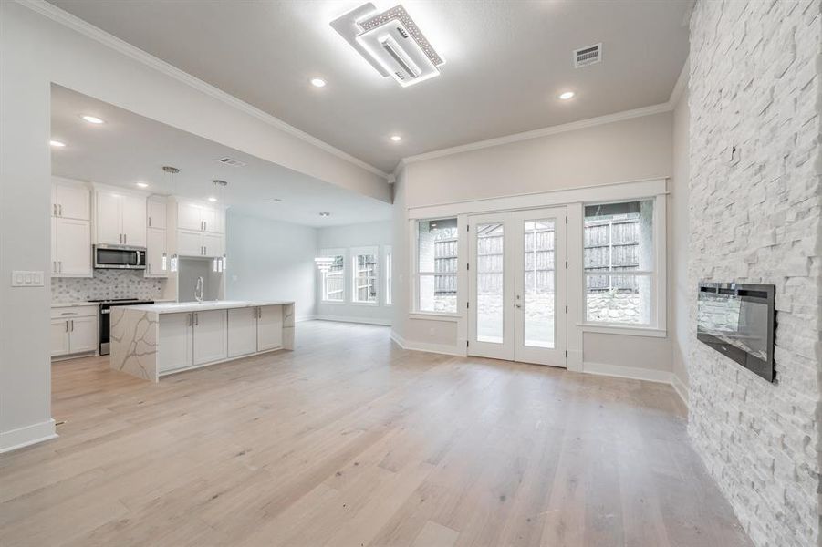 Kitchen with a center island, open floor plan, ornamental molding, white cabinets, and light wood-style flooring